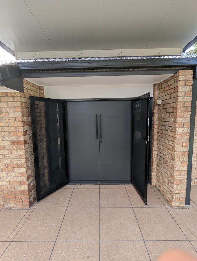 Entry with black double front doors set into a brick facade
