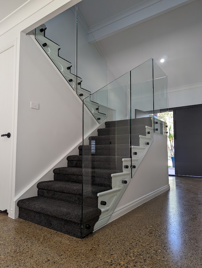 Staircase with a glass balustrade above polished concrete floors