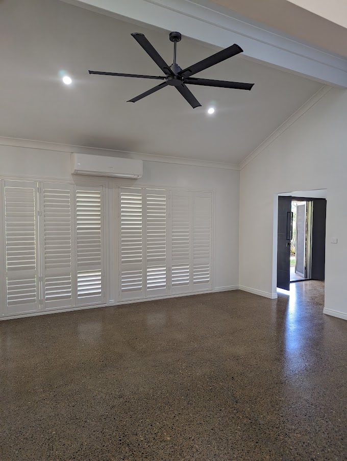 Living room with a raked ceiling, black ceiling fan and polished concrete floors
