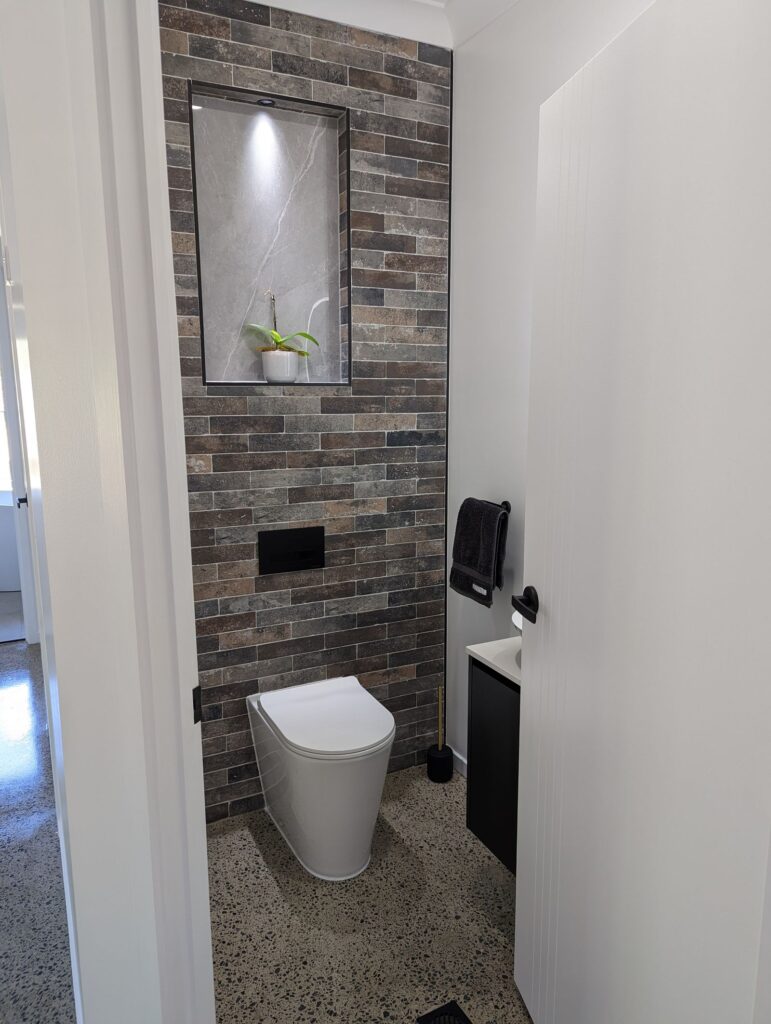 Renovated toilet with a dark brick feature wall, Carrara