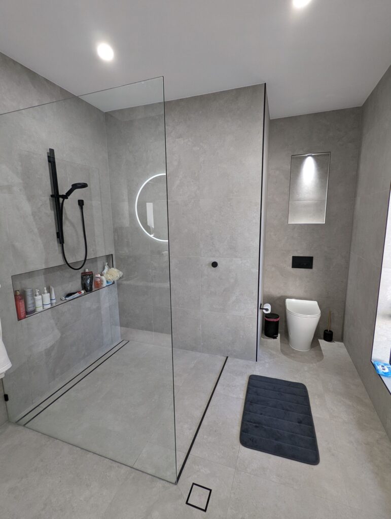 Walk-in shower with black tapware and large-format grey tiles, Carrara