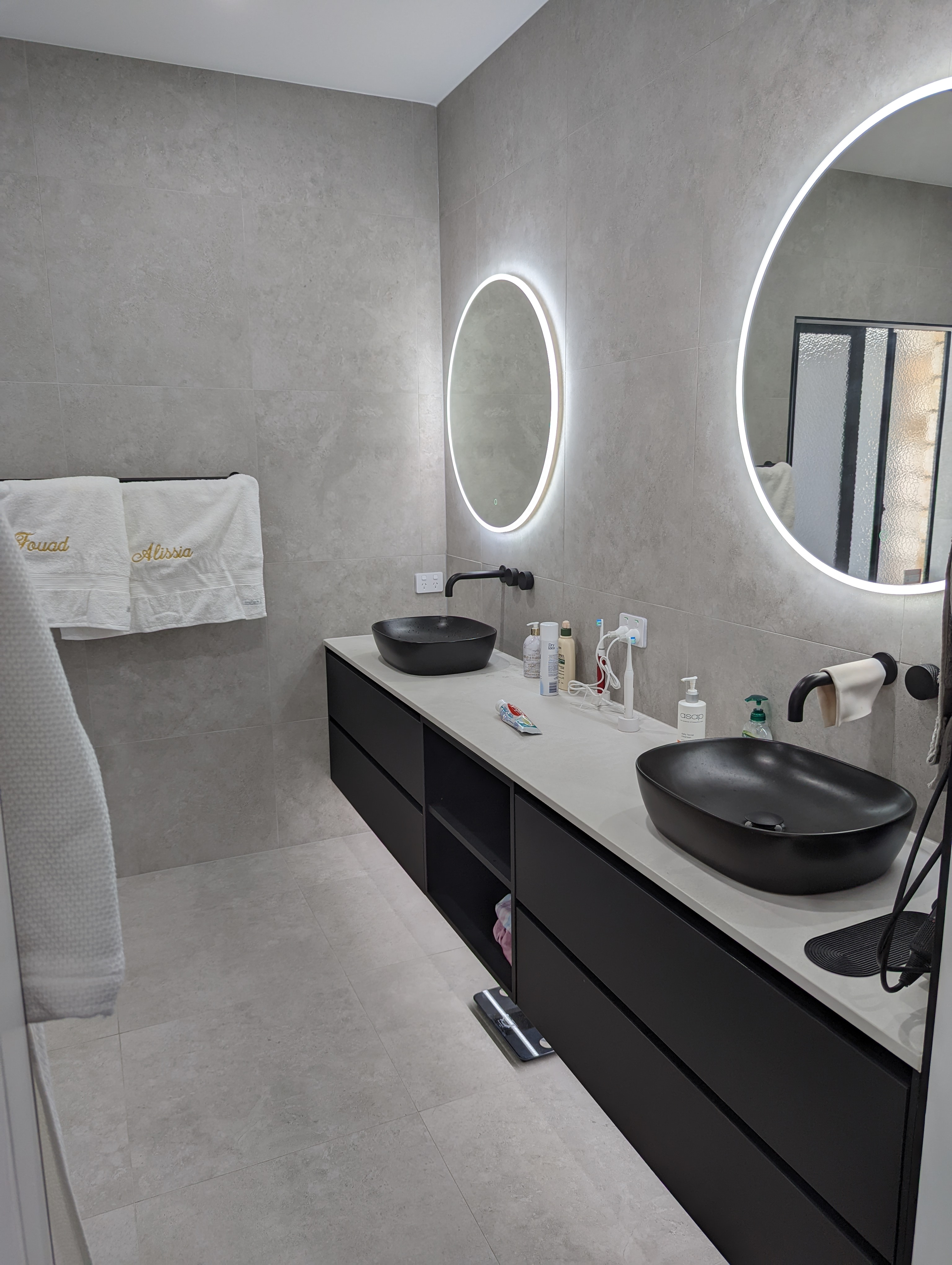 Renovated double vanity in black with twin backlit round mirrors and black basins, Carrara