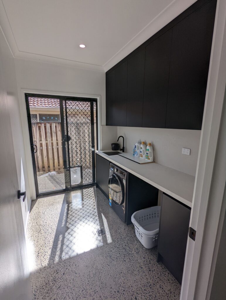 Renovated laundry with black overhead cabinets and a door to the yard, Carrara