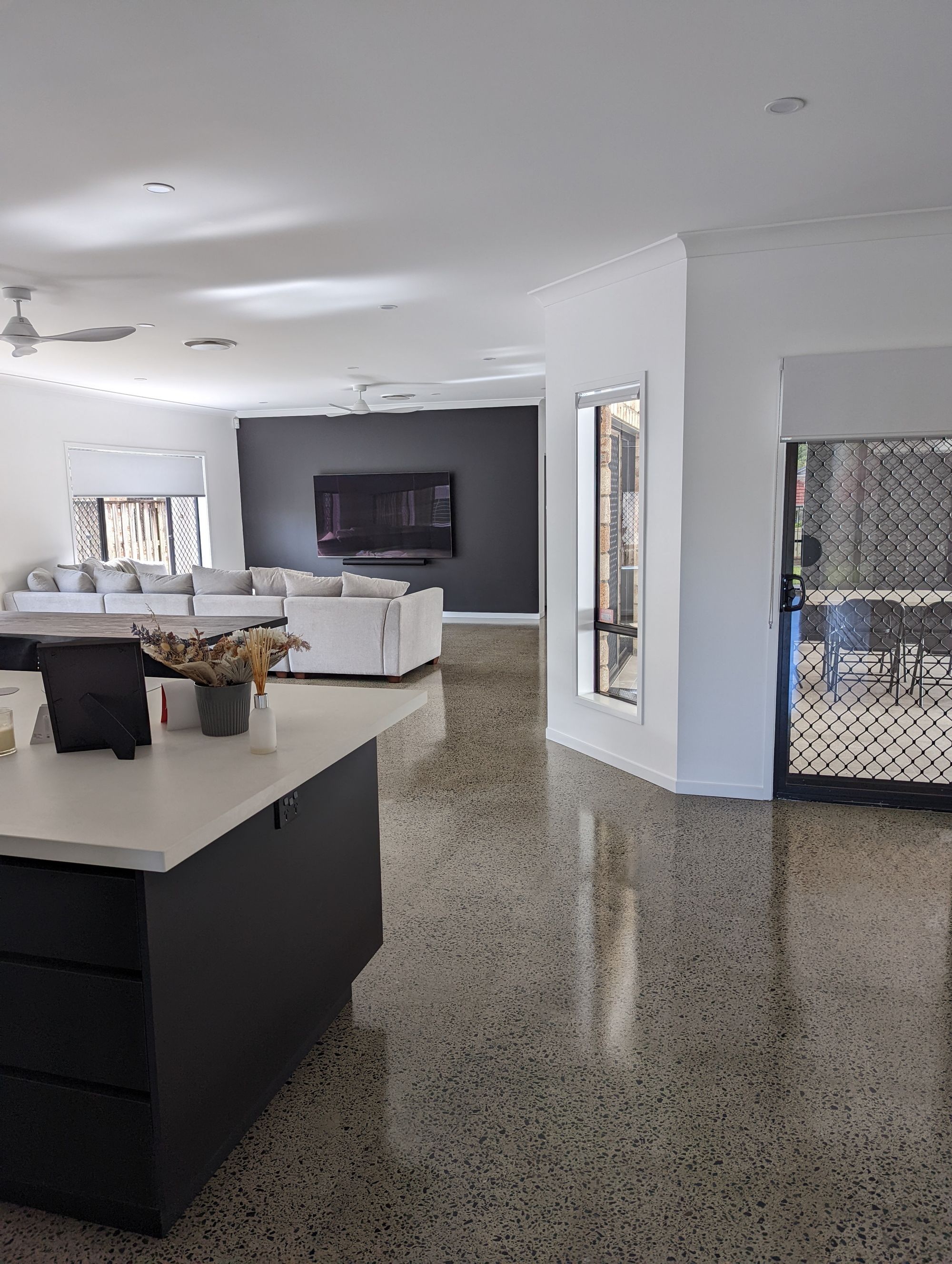 Open-plan kitchen with a black island bench and polished concrete floors, Carrara