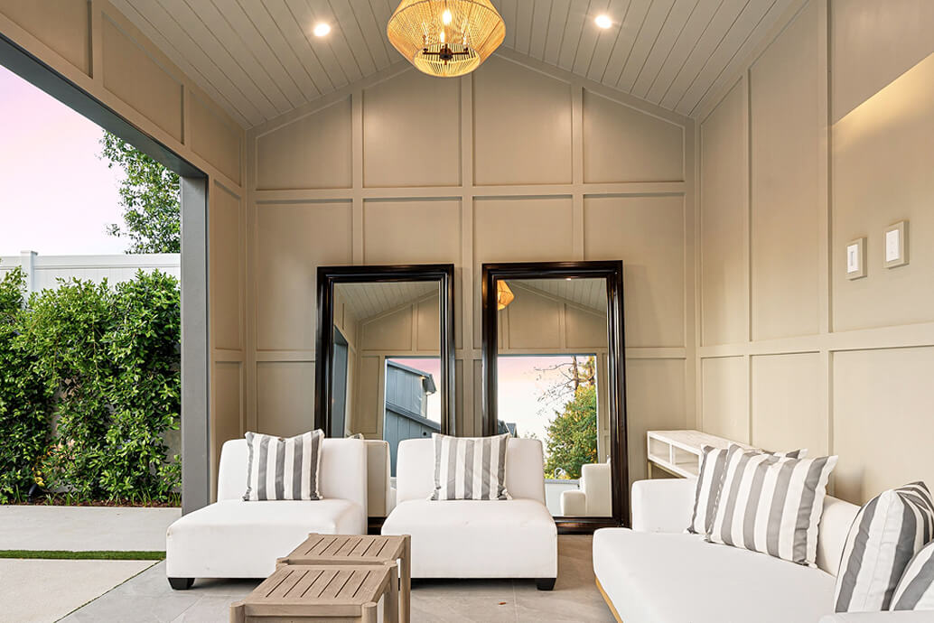 Covered outdoor entertaining area with panelled walls, a pendant light and lounge seating