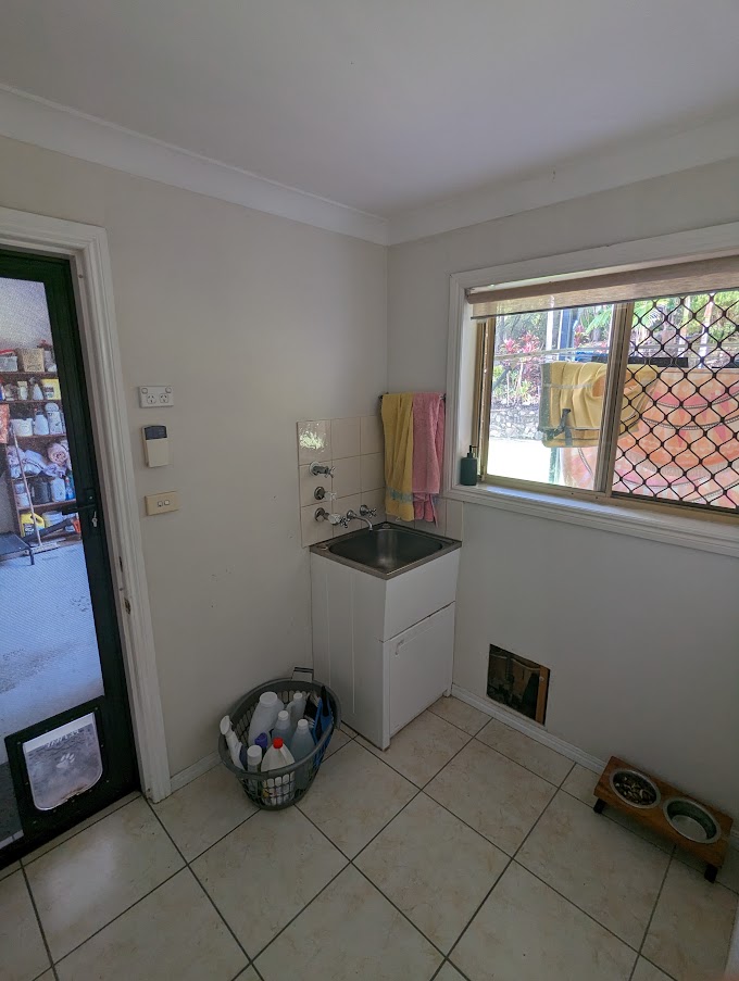 Before renovation: the original laundry with a single cabinet and tiled floor, Gaven
