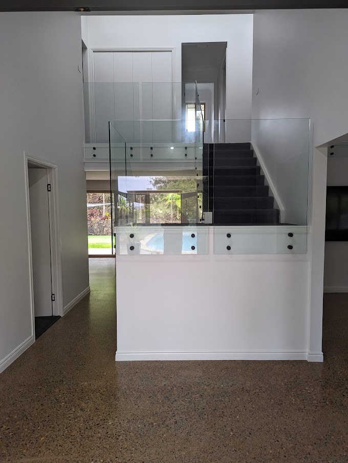 Entry and staircase with a glass balustrade and polished concrete floors after renovation, Gaven