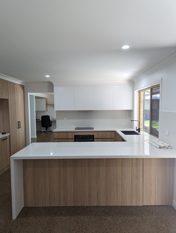 Renovated kitchen with a timber-look peninsula bench and white overhead cabinets
