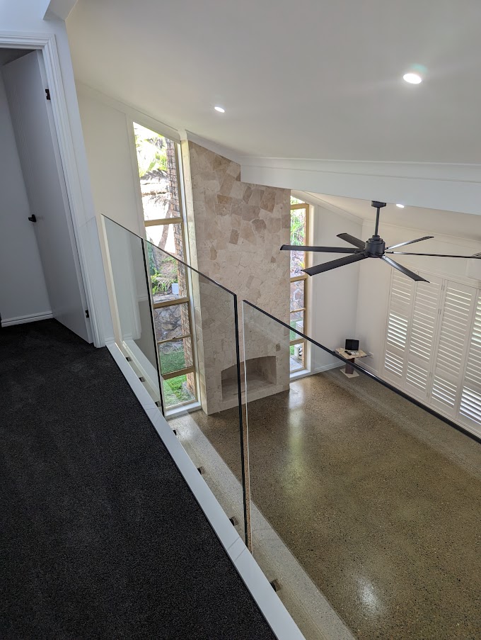 Upstairs landing with a glass balustrade and stone feature wall