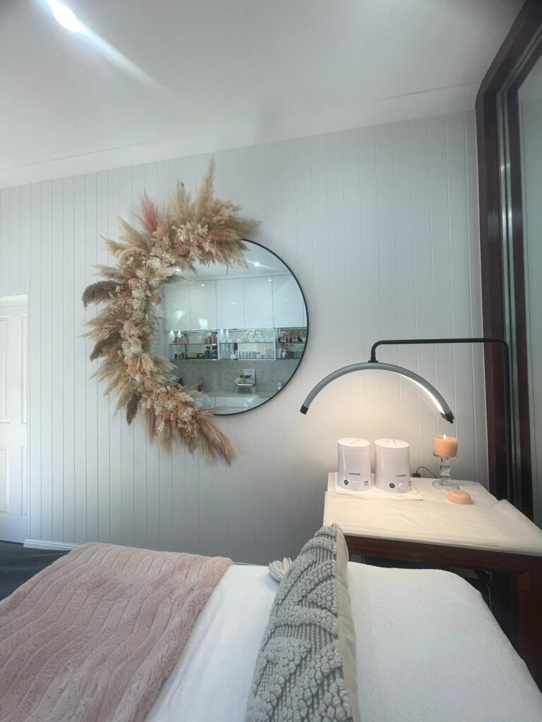 Salon treatment bed beneath a round feature mirror and lamp, Varsity Lakes