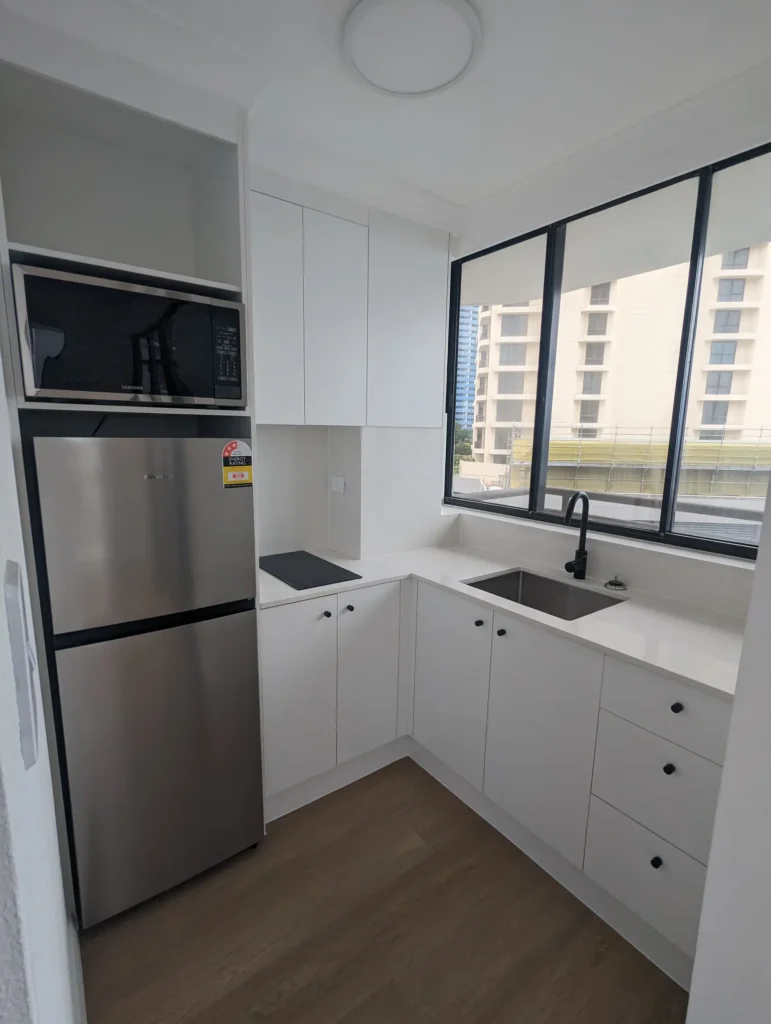 Renovated apartment kitchen with white cabinetry and stone benchtops, Surfers Paradise