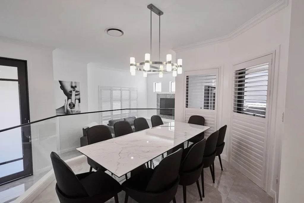 Formal dining area with a marble-look table, black chairs and a linear chandelier, Varsity Lakes
