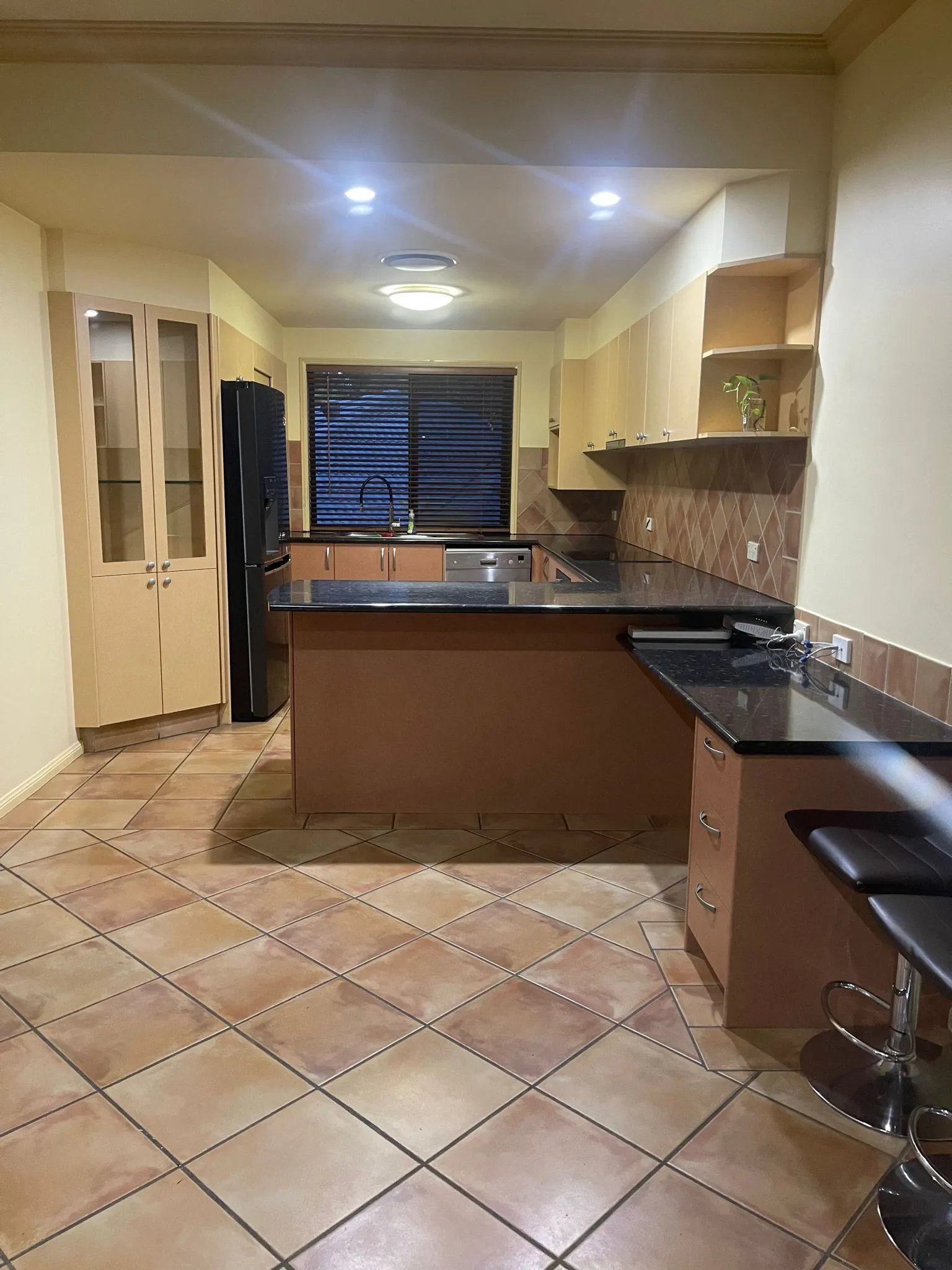Before renovation: the original kitchen with timber cabinetry and terracotta floor tiles, Varsity Lakes