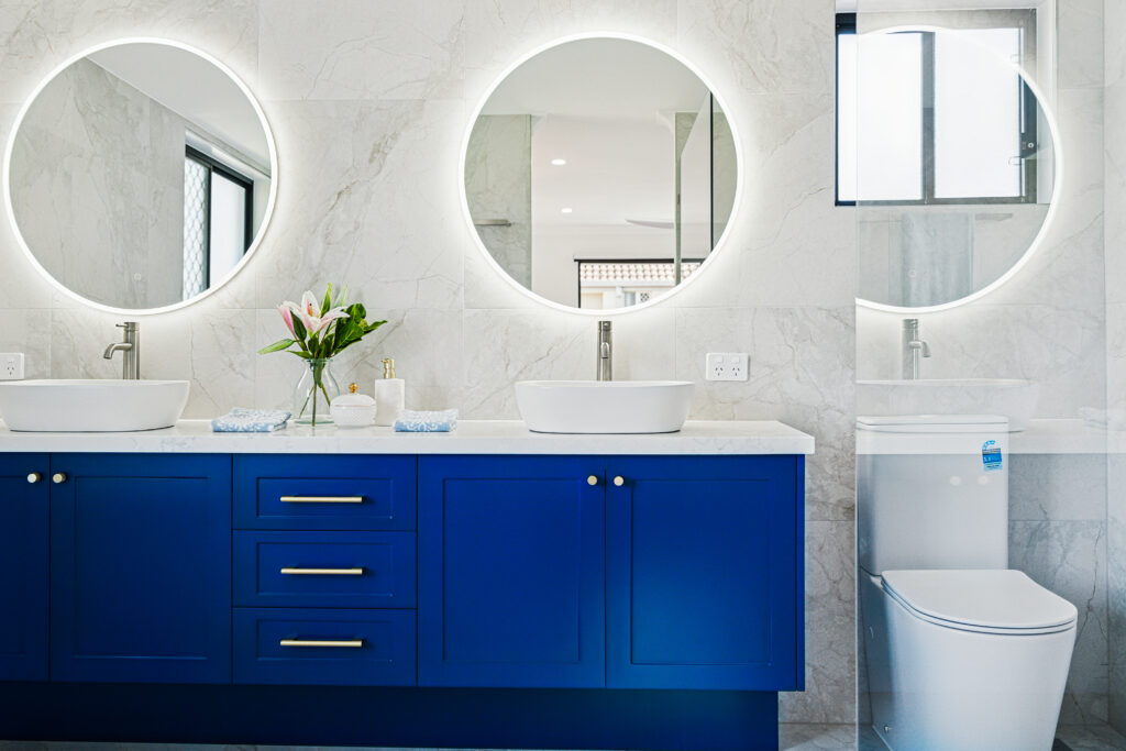 Renovated bathroom with navy double vanity, twin round backlit mirrors and marble-look tiles, Robina