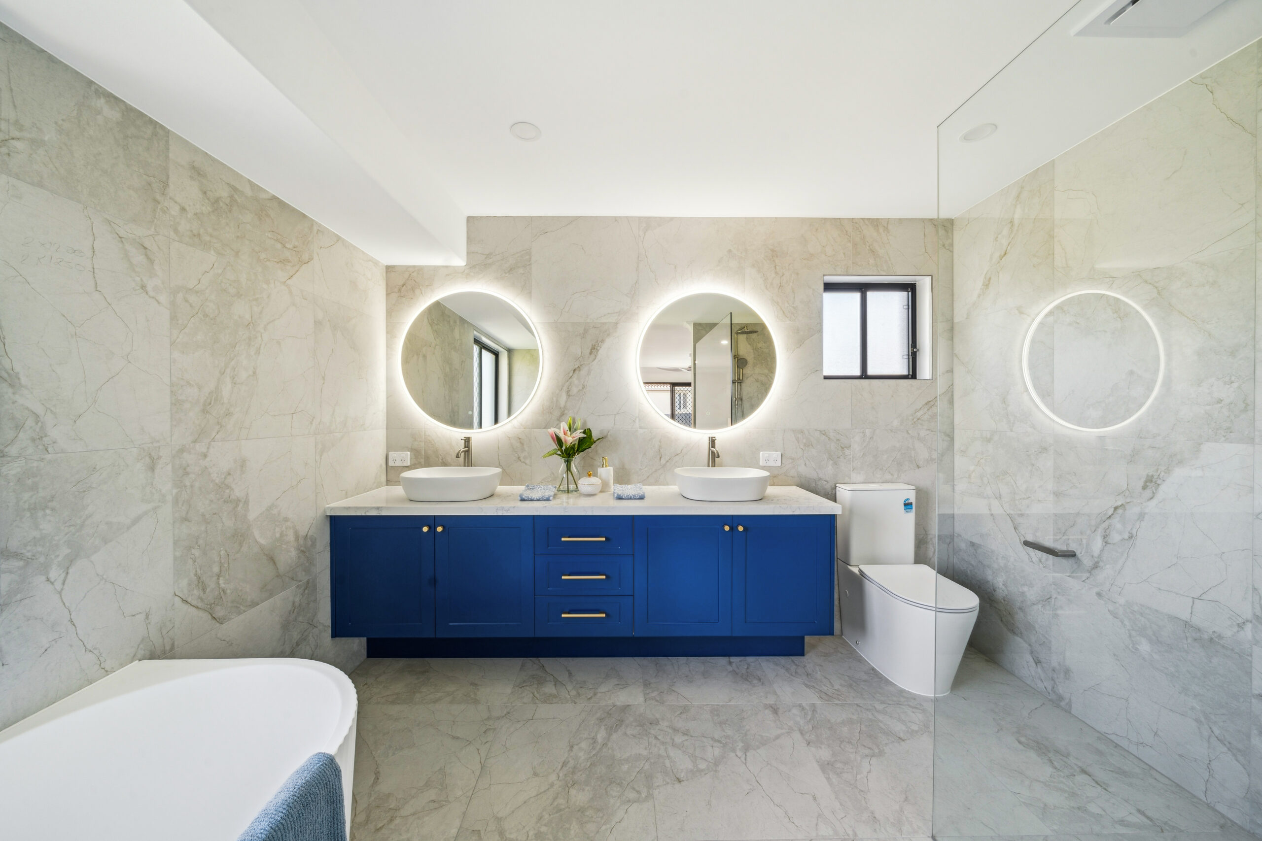 Renovated ensuite with deep blue double vanity, twin backlit mirrors and freestanding bath, Robina