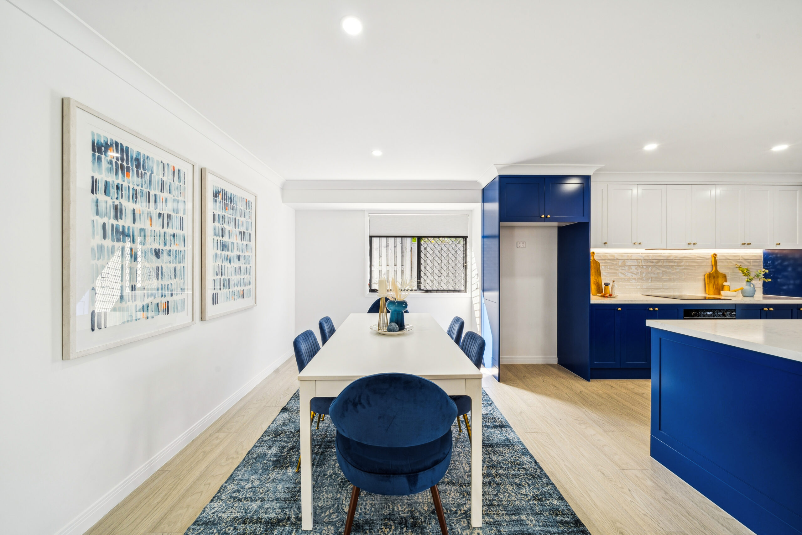 Dining area with white table and navy chairs beside the renovated navy kitchen, Robina
