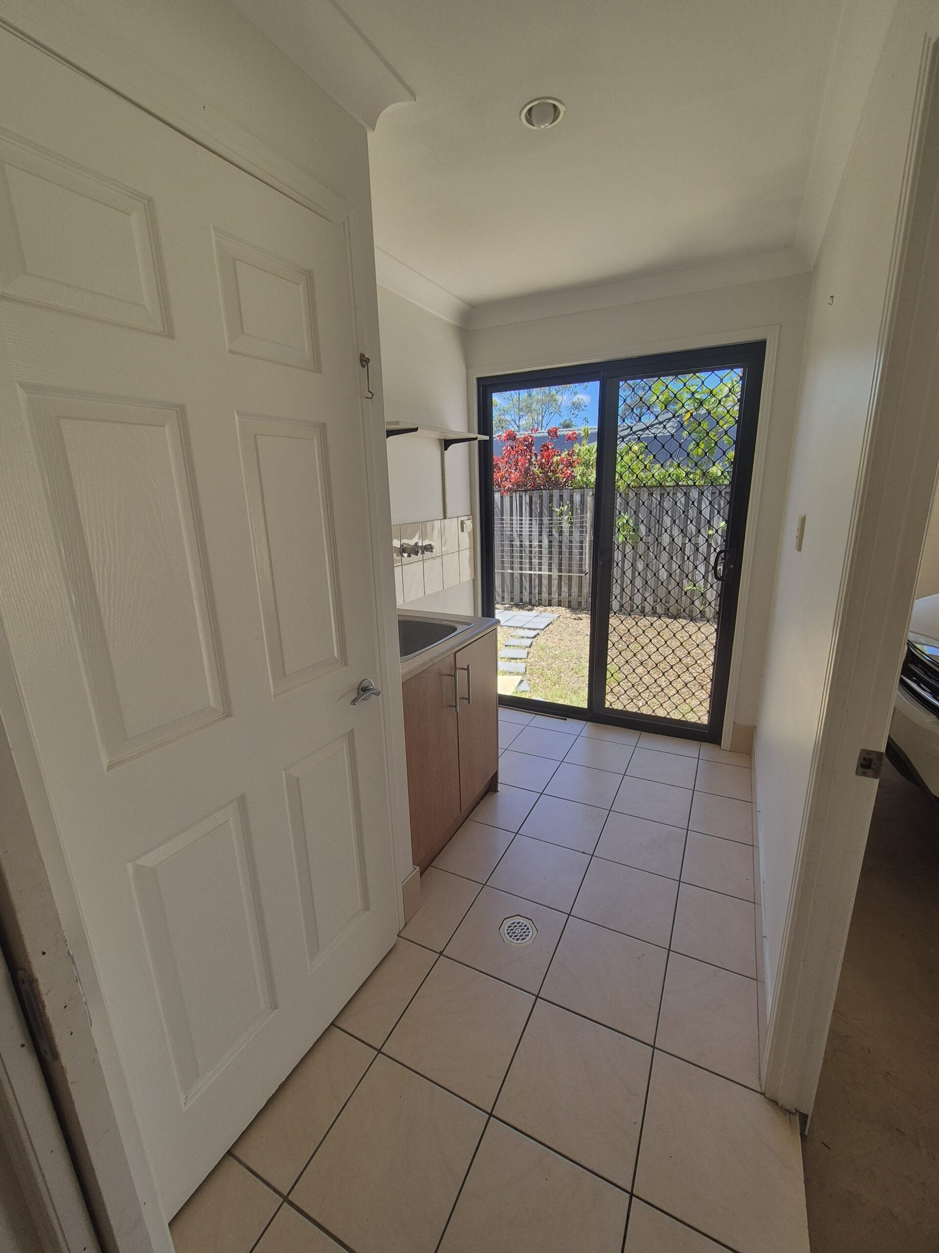 Before renovation: the hallway looking into the original kitchen with cream floor tiles, Robina