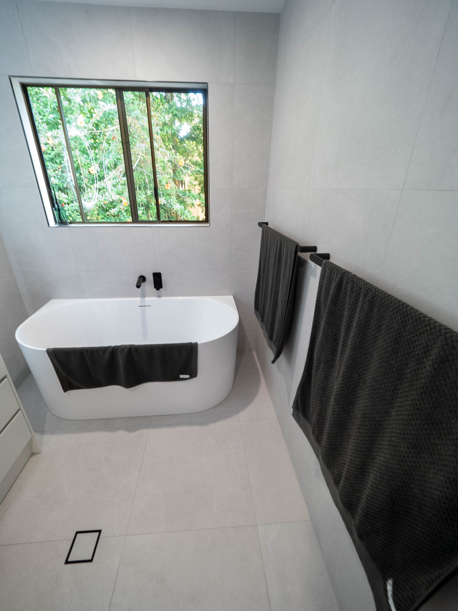 Freestanding bath beneath the window with a black towel rail, Lower Beechmont