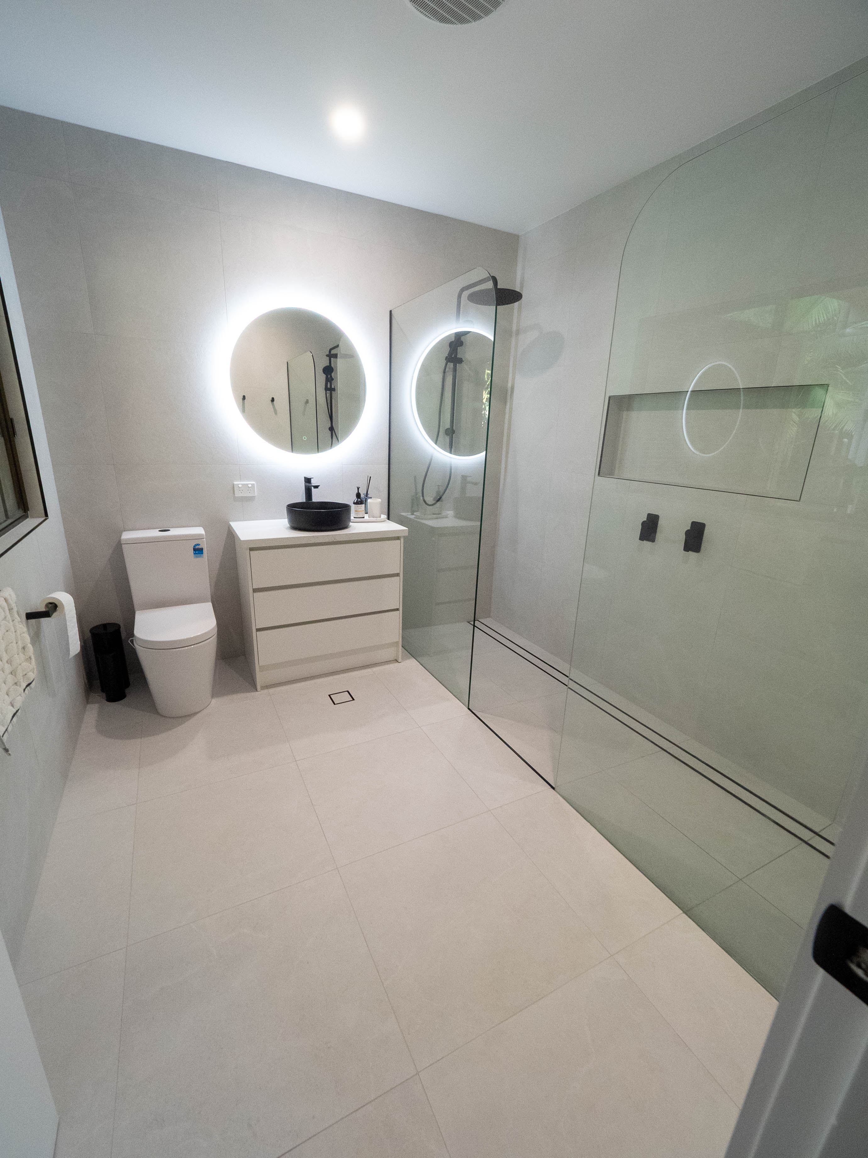Renovated bathroom with a backlit round mirror, black basin and walk-in shower, Lower Beechmont