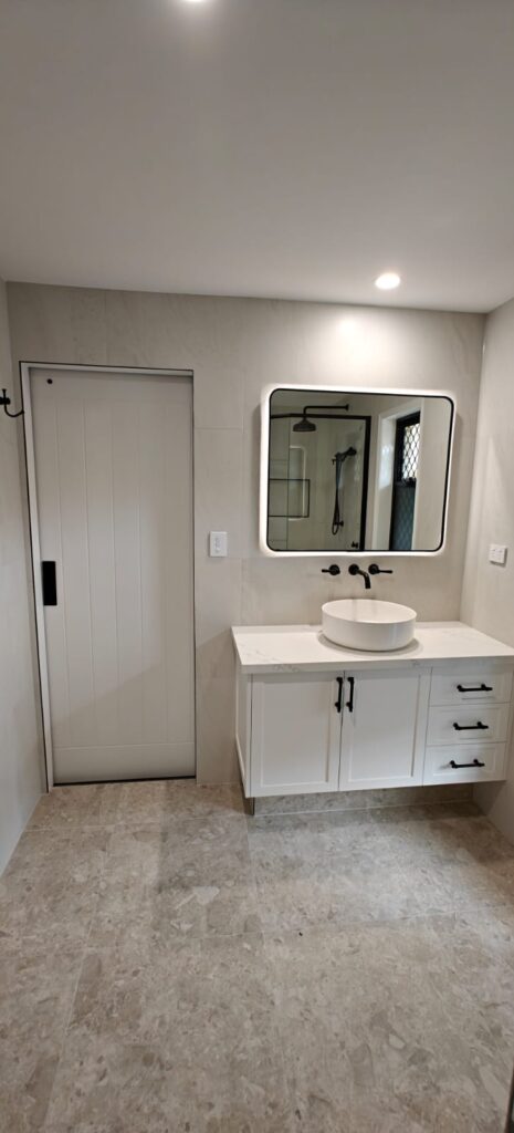 Renovated bathroom vanity with a backlit square mirror and white shaker cabinetry, Ormeau