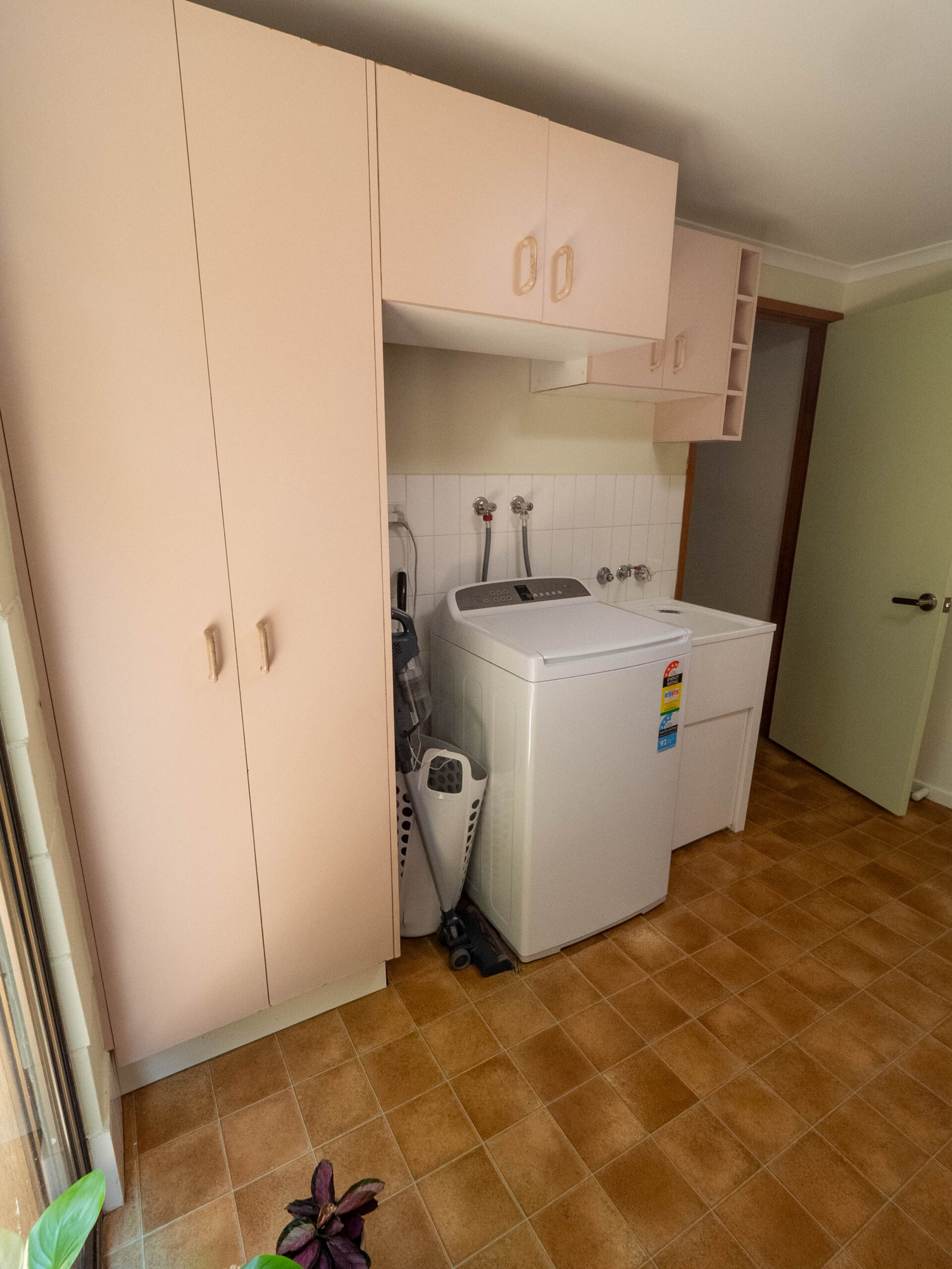 Before renovation: the original laundry with cream cabinetry and a top-loading washer, Lower Beechmont