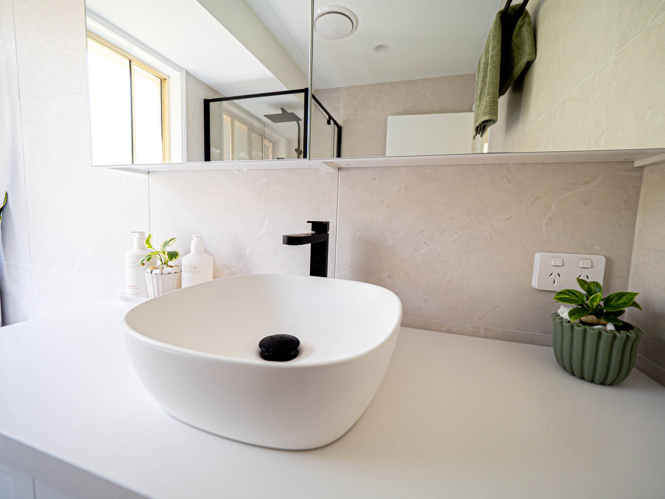 Close-up of a white vessel basin on a stone benchtop with black tapware, Gaven