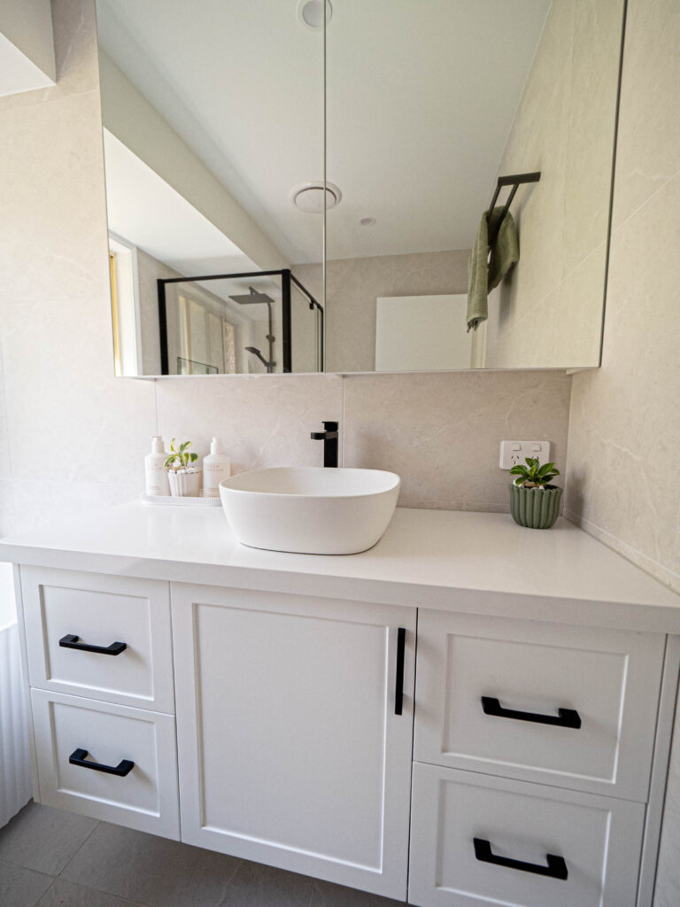 Renovated bathroom with white shaker cabinetry, black handles and a mirrored cabinet, Gaven