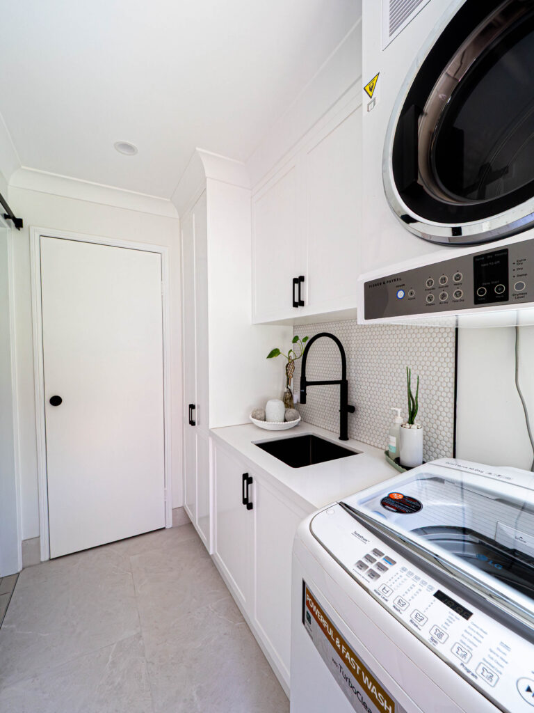 Renovated laundry with a wall-mounted dryer, black tapware and white cabinetry, Gaven