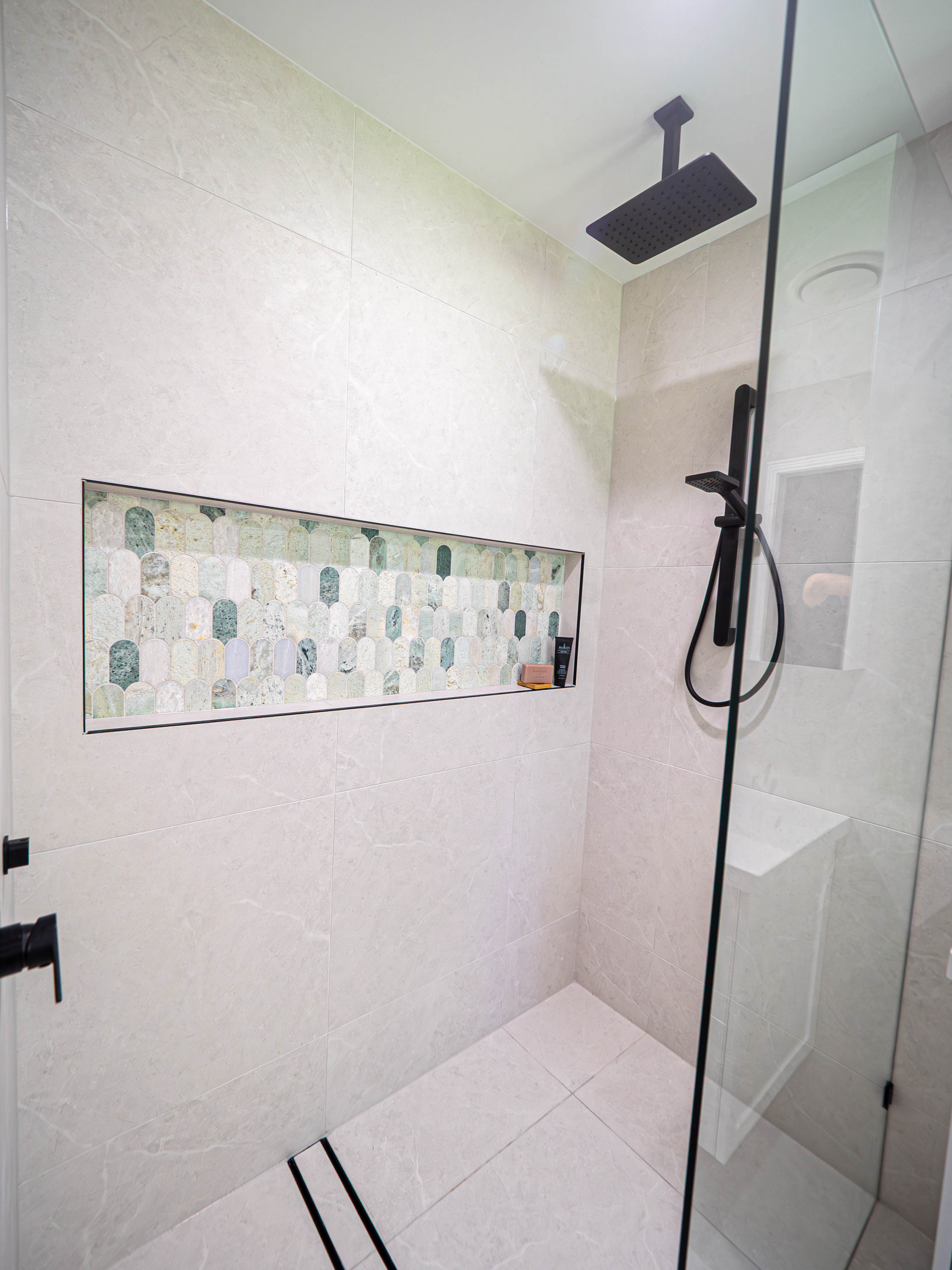Walk-in shower with a black rainfall shower head and mosaic feature niche, Gaven