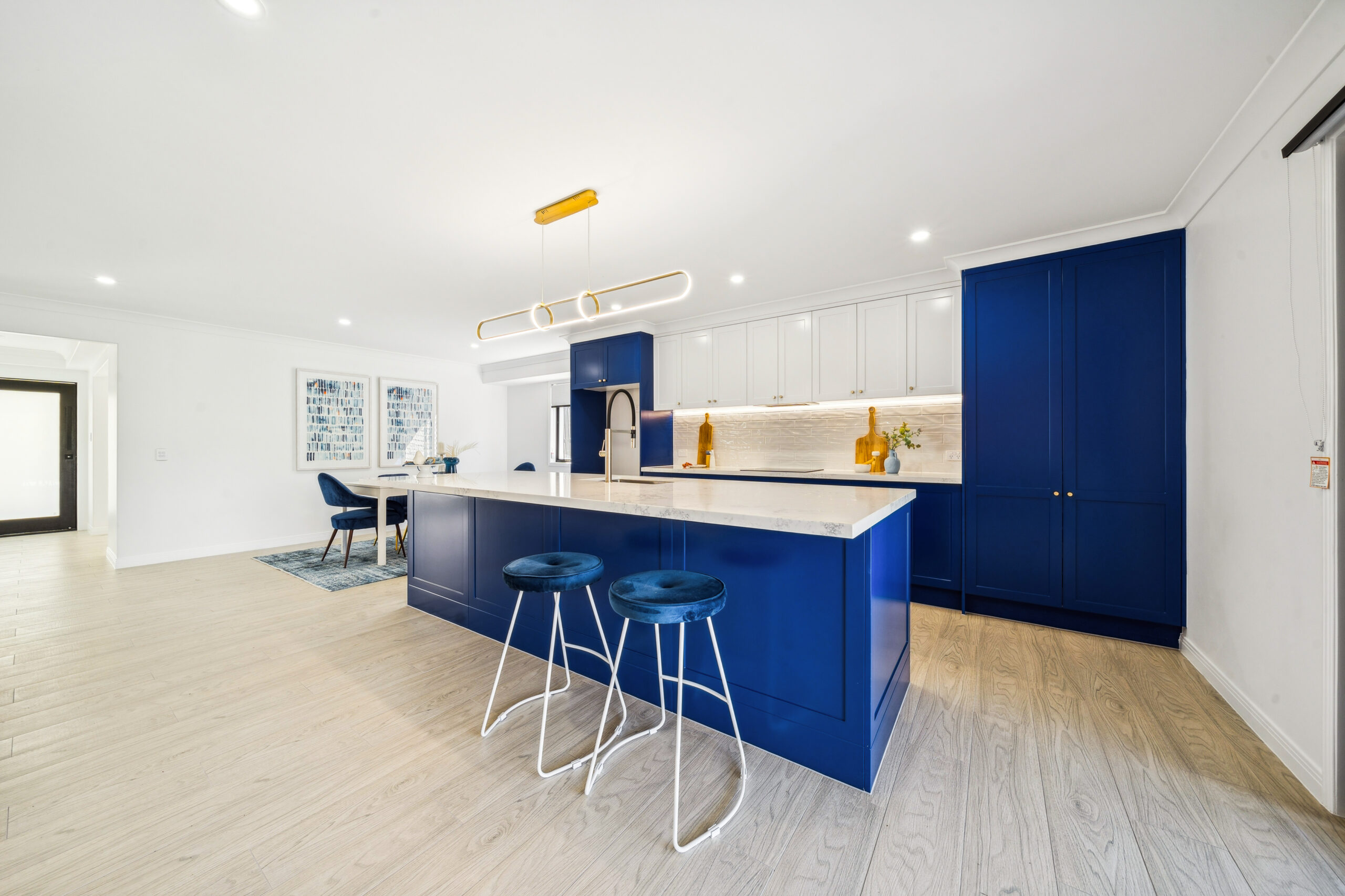 Navy shaker kitchen renovation with a stone waterfall island, brass tapware and white overhead cabinets